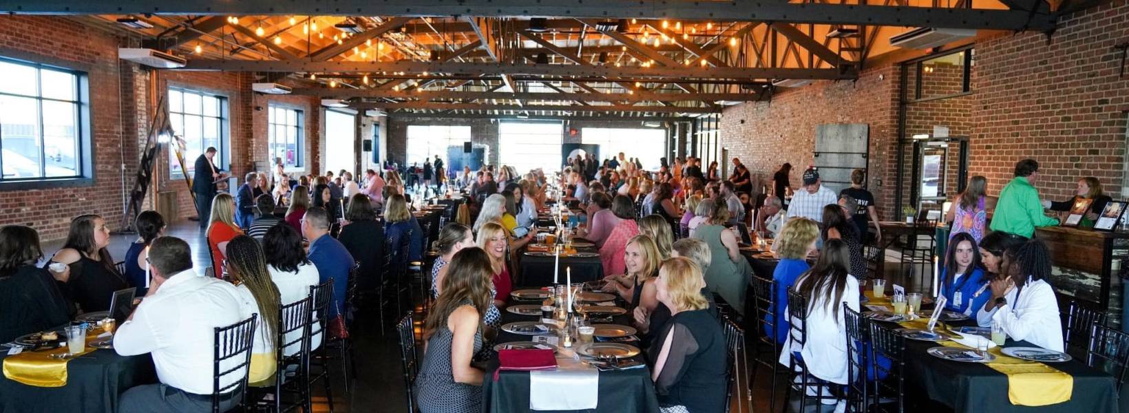 People in a room eating at three rows of tables