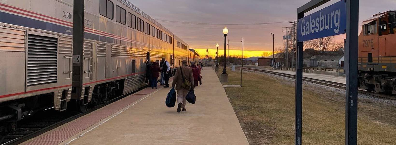 Train pullin in to a station with a mural in the background